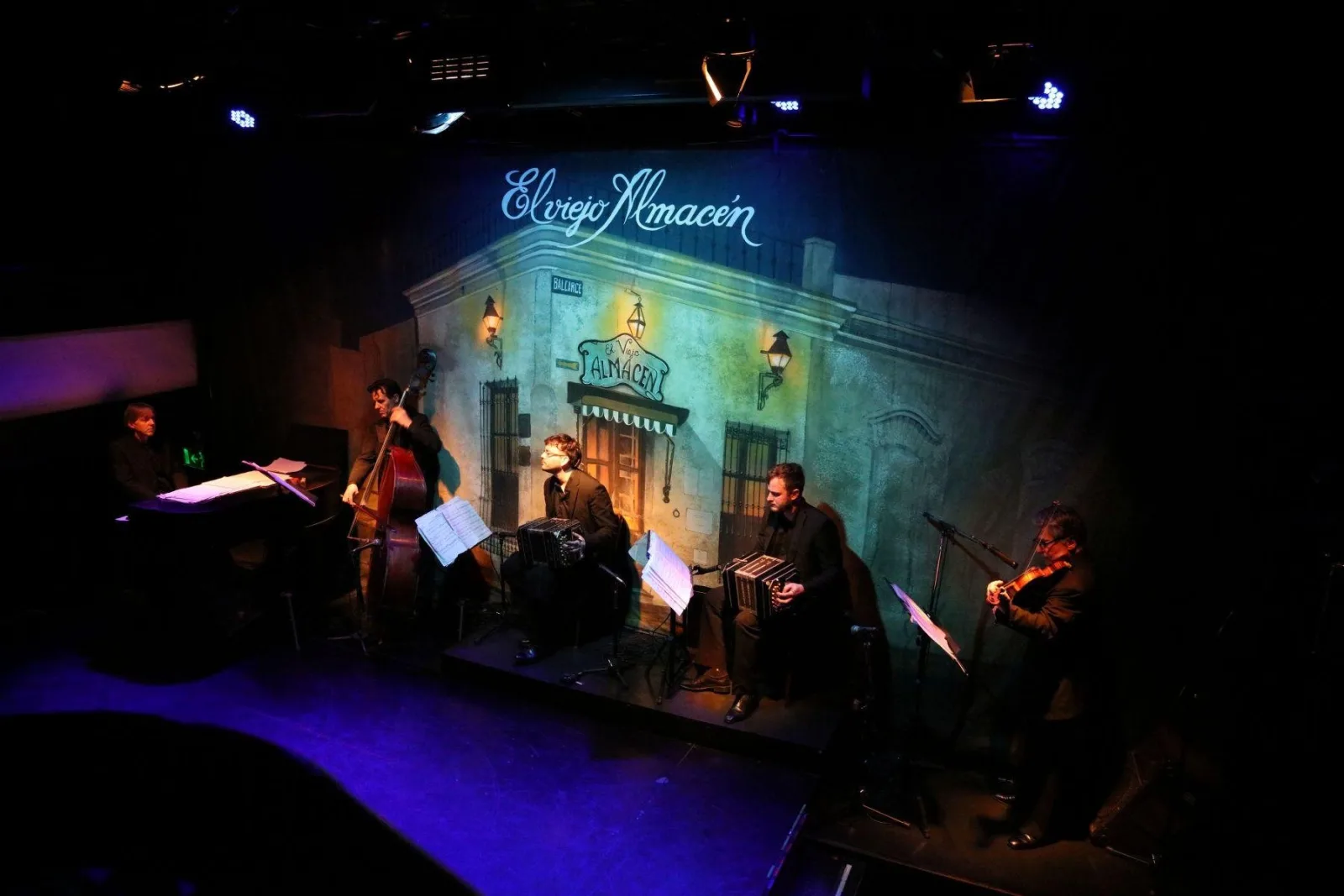 The El Viejo Almacén stage with musicians seated in front of the venue's painted backdrop
