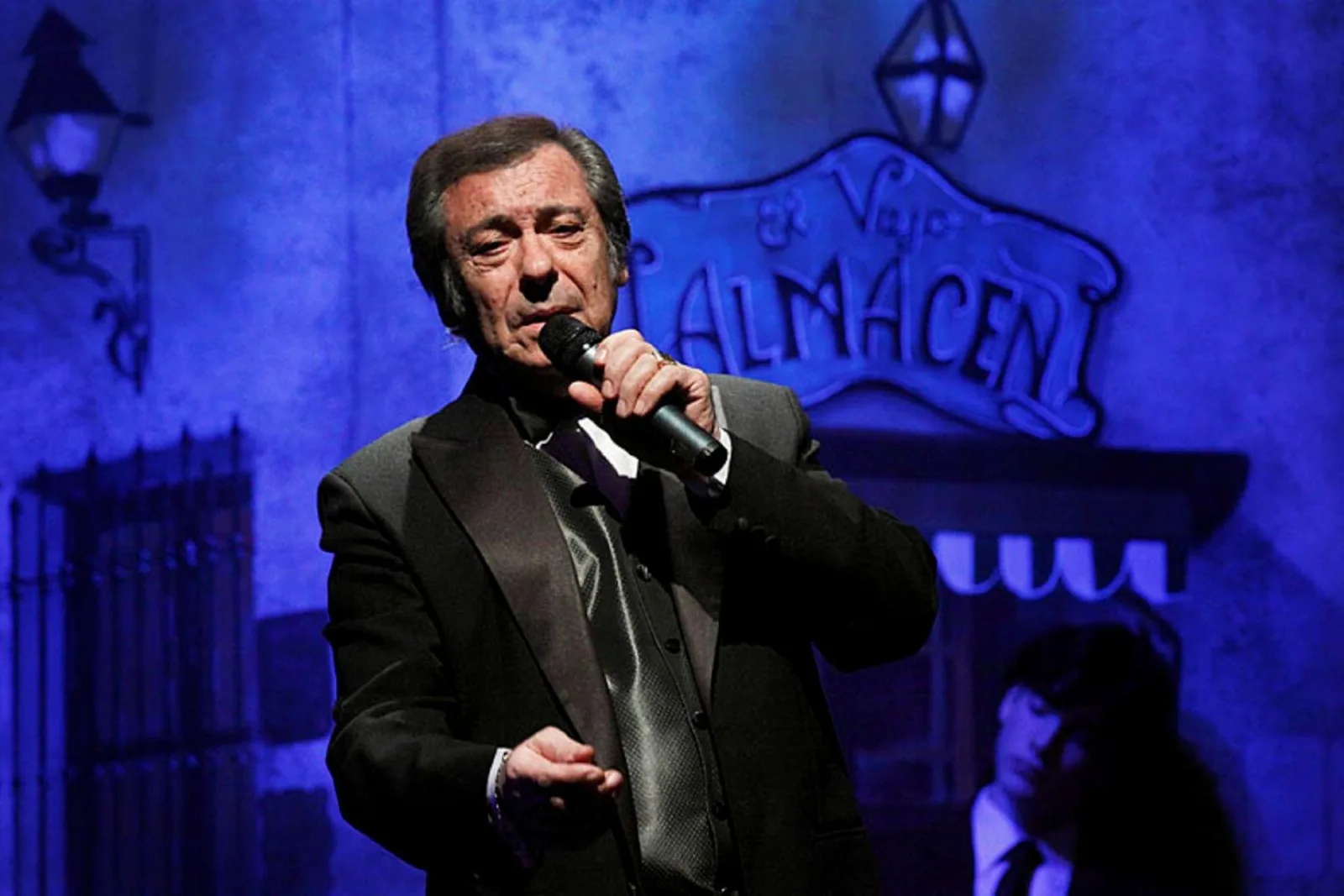 A male tango singer performing at the microphone in front of the El Viejo Almacén sign