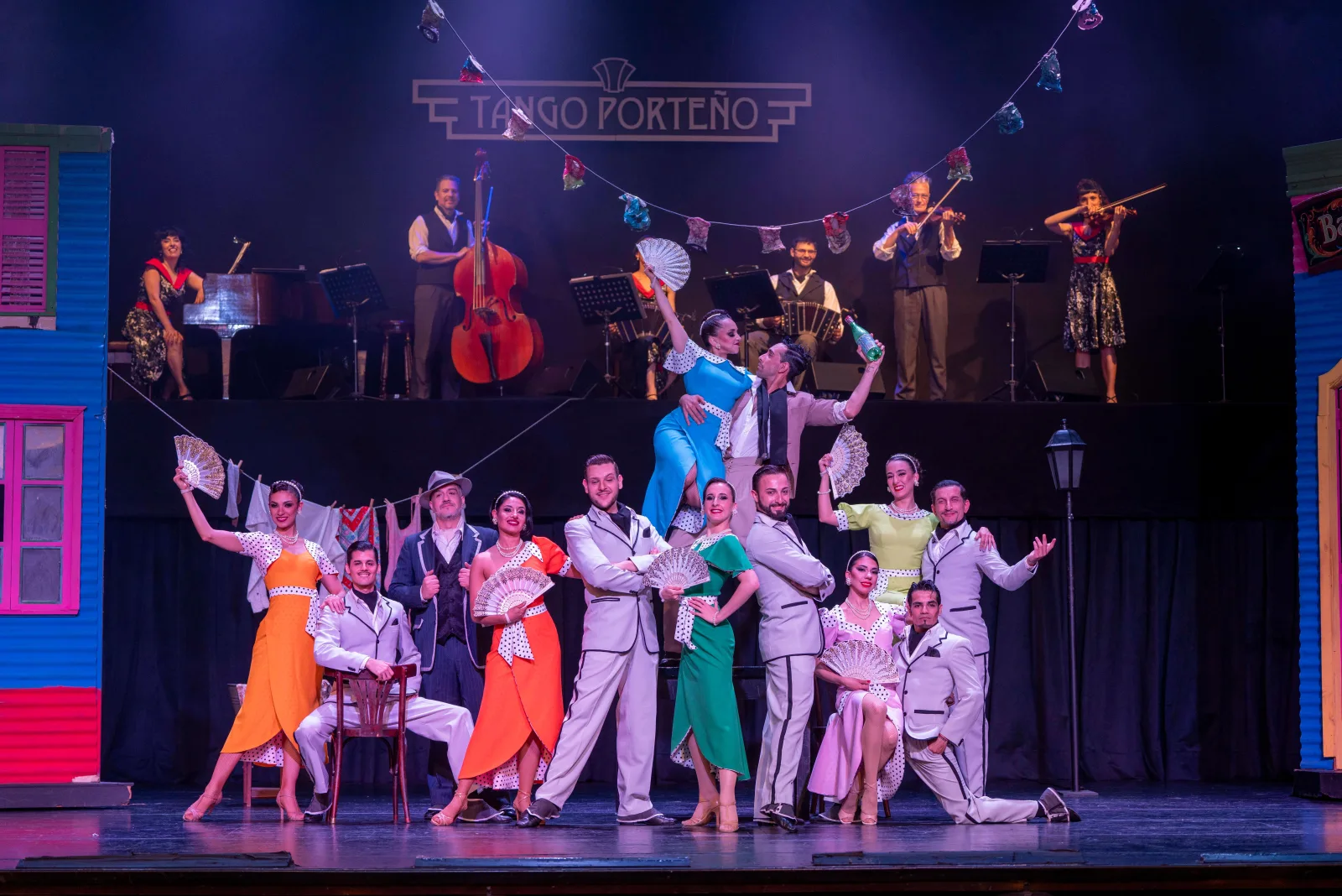 The full Tango Porteño cast in coloured costume during a finale with the orchestra behind