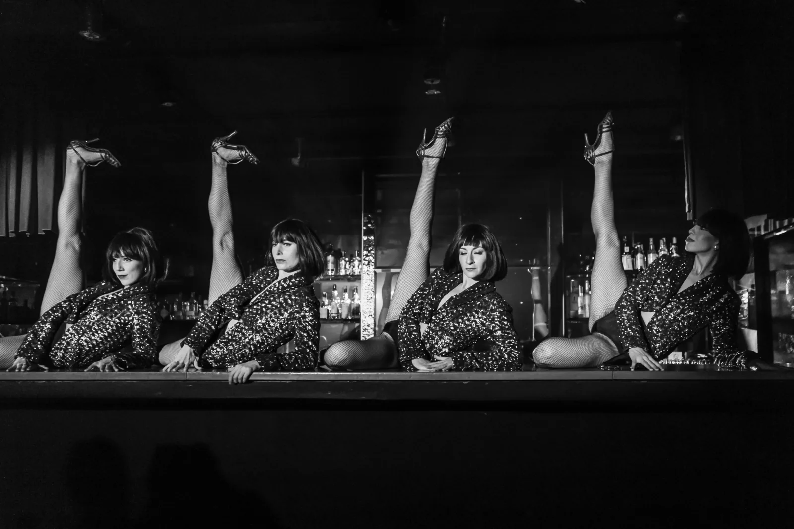 Black and white image of the Rojo Tango chorus line with arms raised