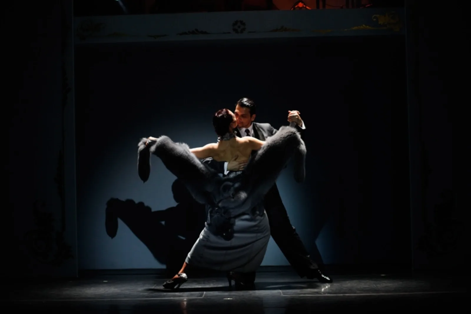 A tango couple in a low crouching pose under a single spotlight at Café de los Angelitos