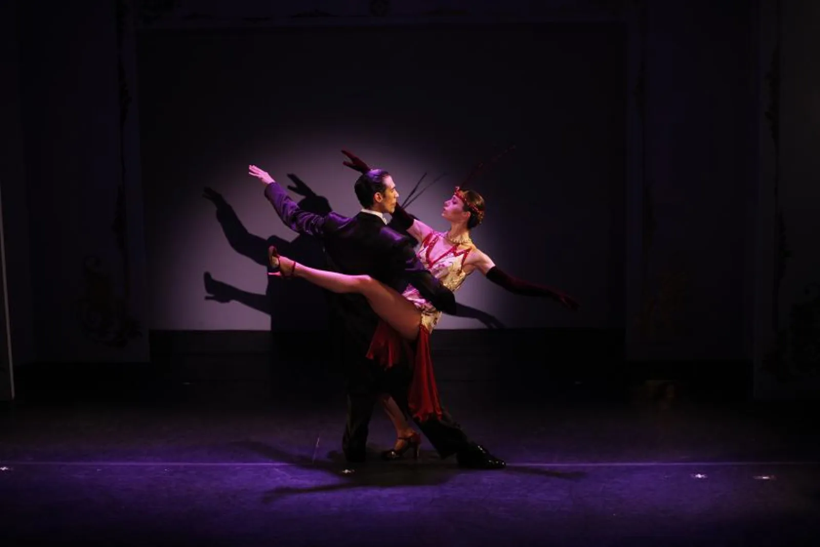 A pair of dancers lifted in purple stage light at Café de los Angelitos
