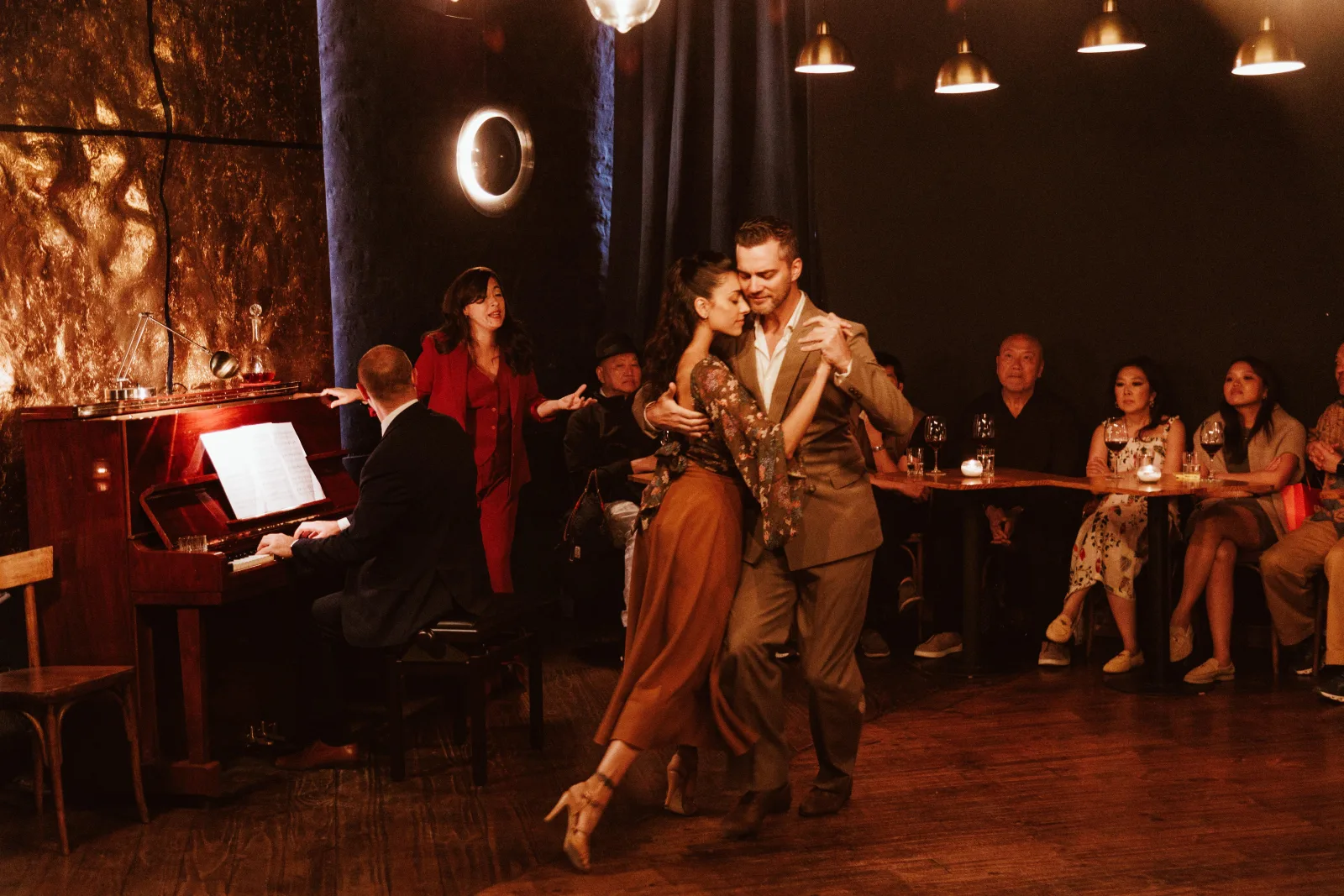 A tango couple dancing between the audience tables in the small Secreto Tango room