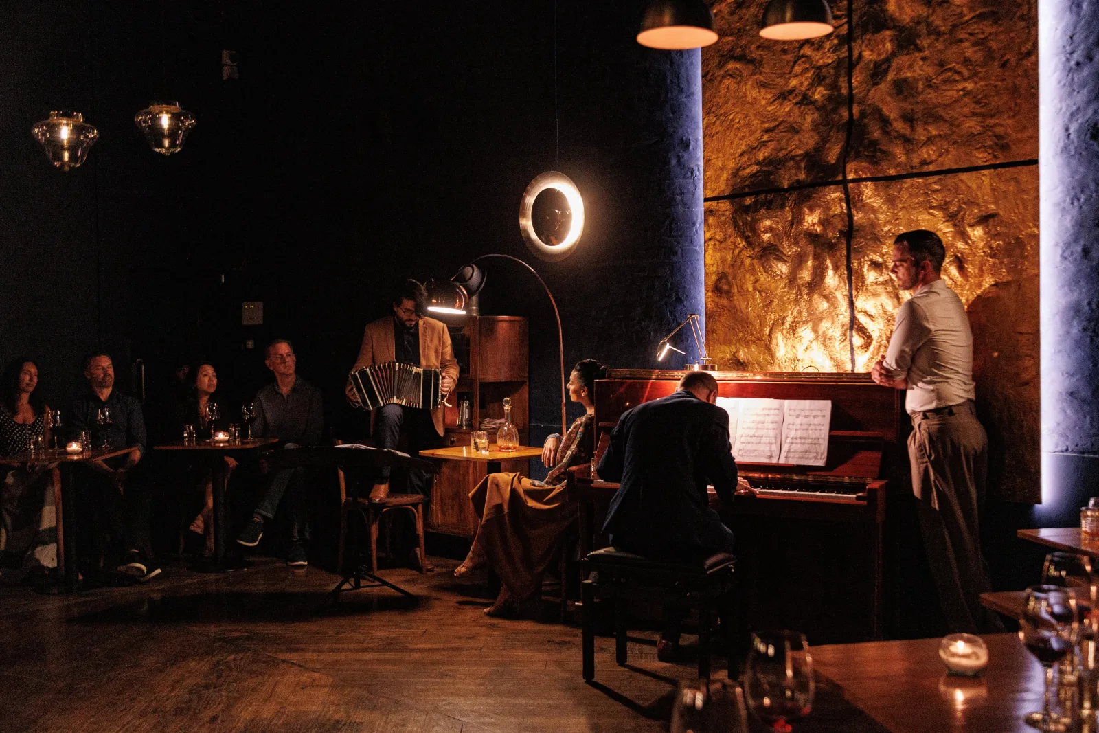 The Secreto Tango venue lit by lamps, with a pianist and a few cabaret tables