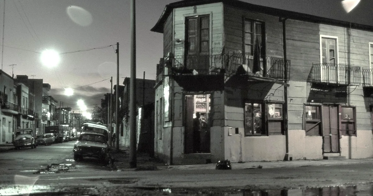 An old wooden corner building in La Boca at dusk, its balconies and lit doorway typical of the bars where tango took root